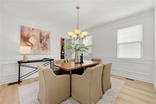 325 Cranbrooke Cir, Suwanee, GA 30024 - dining area with a chandelier, light wood-style floors, a decorative wall, ornamental molding, and wainscoting