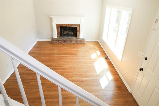 unfurnished living room with a brick fireplace and hardwood / wood-style floors