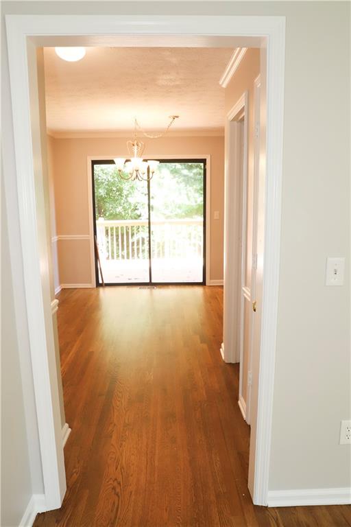 hall featuring wood-type flooring, an inviting chandelier, and ornamental molding