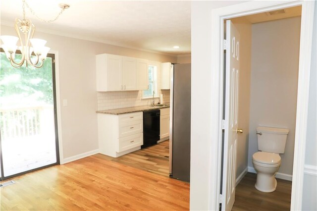 interior space featuring light wood-type flooring, stainless steel refrigerator, white cabinetry, black dishwasher, and tasteful backsplash