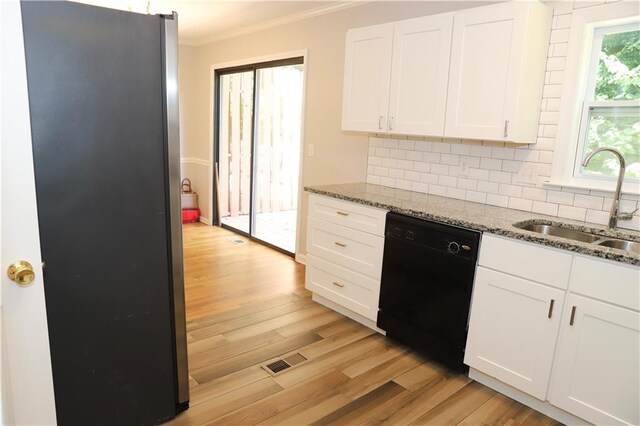 kitchen with stone counters, stainless steel fridge, dishwasher, sink, and light hardwood / wood-style floors