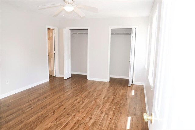 unfurnished bedroom featuring light hardwood / wood-style flooring, ceiling fan, and multiple closets