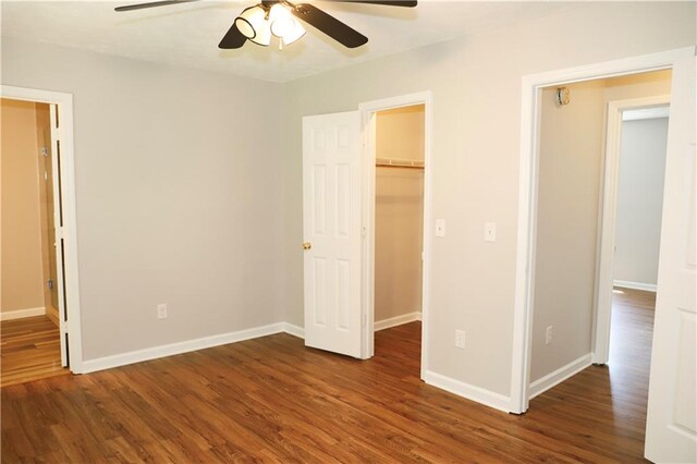 unfurnished bedroom with a closet, ceiling fan, dark hardwood / wood-style floors, and a spacious closet