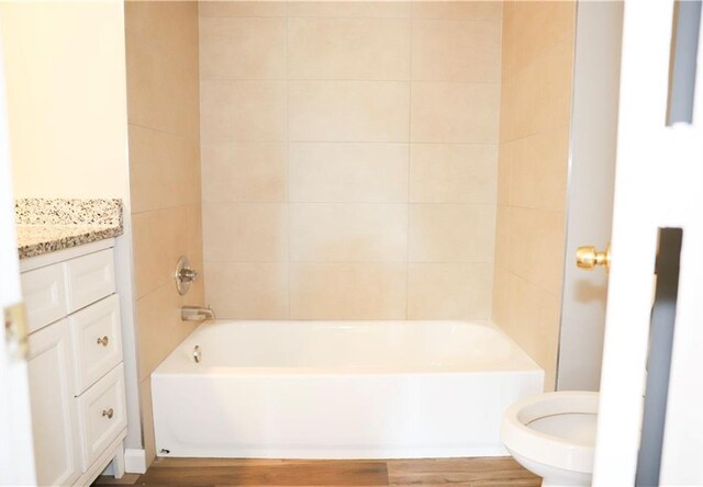 full bathroom featuring tiled shower / bath, vanity, toilet, and hardwood / wood-style flooring