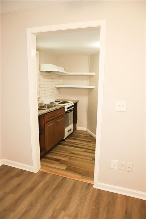 kitchen featuring white stove, dark wood-type flooring, premium range hood, and tasteful backsplash