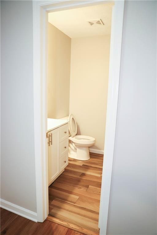 bathroom featuring wood-type flooring, toilet, and vanity