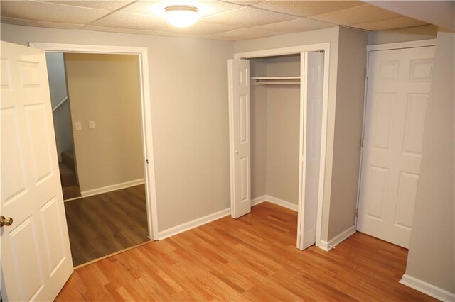 unfurnished bedroom featuring light hardwood / wood-style floors, a closet, and a drop ceiling