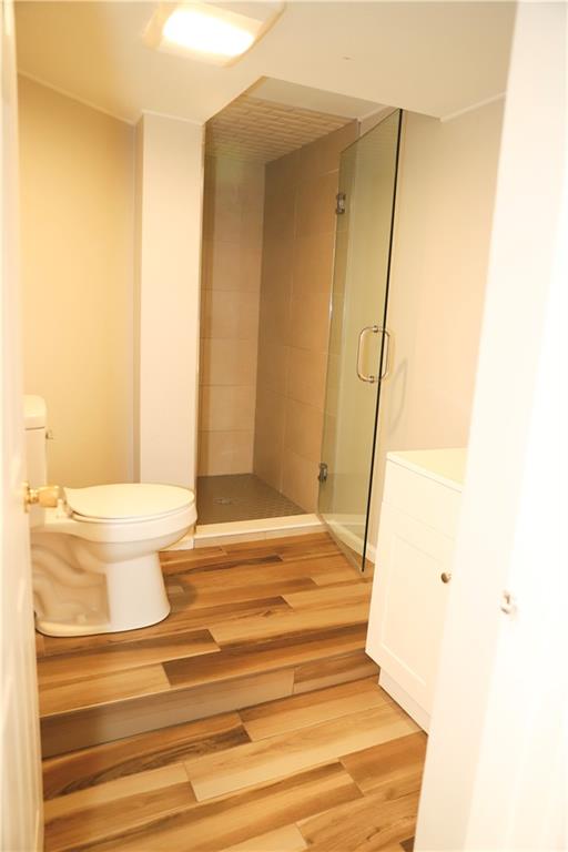 bathroom featuring vanity, toilet, an enclosed shower, and hardwood / wood-style flooring