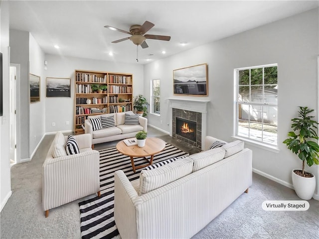 living area featuring baseboards, ceiling fan, a tiled fireplace, and recessed lighting