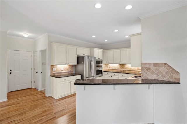 kitchen with stainless steel appliances, ornamental molding, light hardwood / wood-style floors, kitchen peninsula, and backsplash