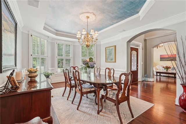 3235 Munsey Ct, Cumming, GA 30041 - dining space featuring a tray ceiling, arched walkways, wood finished floors, a chandelier, and crown molding