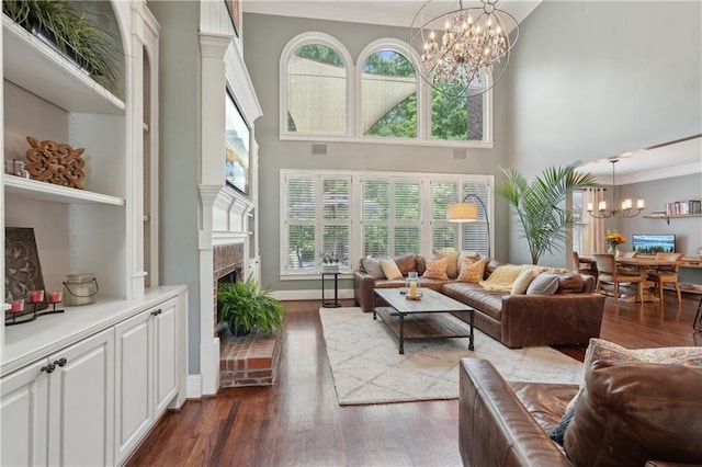 3235 Munsey Ct, Cumming, GA 30041 - living room featuring a chandelier, a fireplace with raised hearth, dark wood finished floors, plenty of natural light, and a high ceiling