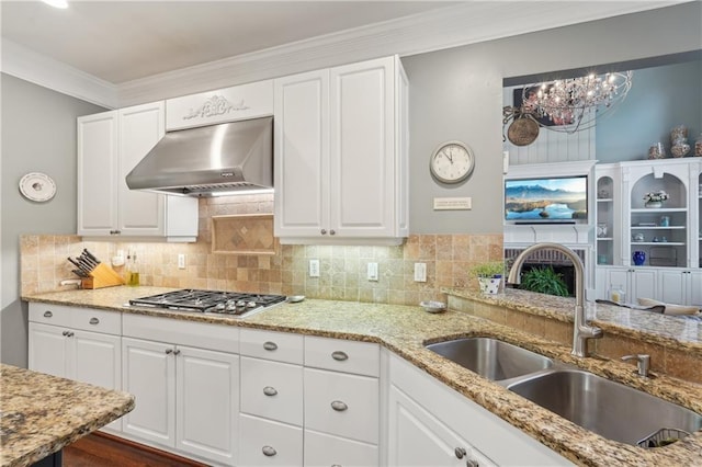 3235 Munsey Ct, Cumming, GA 30041 - kitchen with under cabinet range hood, stainless steel gas cooktop, light stone counters, white cabinets, and ornamental molding