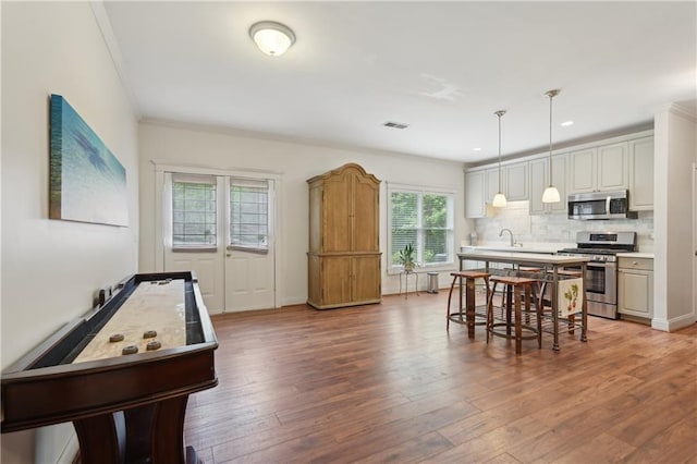 3235 Munsey Ct, Cumming, GA 30041 - kitchen with stainless steel appliances, crown molding, wood finished floors, tasteful backsplash, and light countertops
