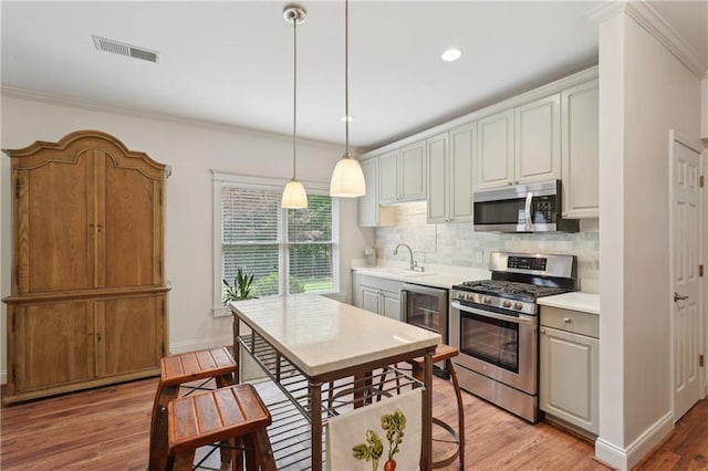 3235 Munsey Ct, Cumming, GA 30041 - kitchen featuring appliances with stainless steel finishes, light wood finished floors, backsplash, light countertops, and crown molding