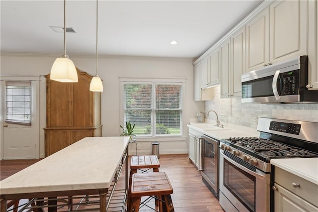 3235 Munsey Ct, Cumming, GA 30041 - kitchen with appliances with stainless steel finishes, light wood-type flooring, plenty of natural light, crown molding, and recessed lighting