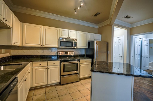 kitchen with light tile patterned flooring, stainless steel appliances, visible vents, ornamental molding, and backsplash