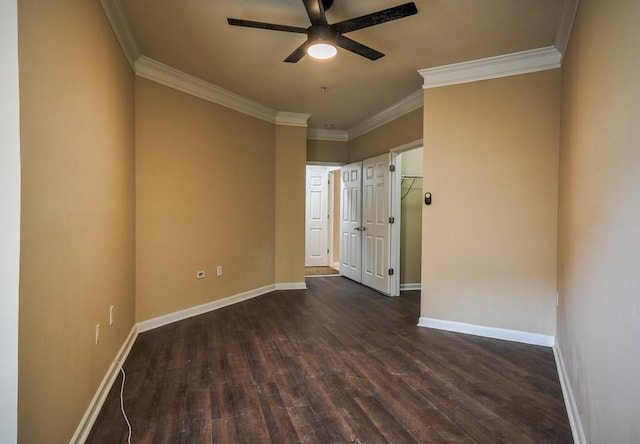 empty room with a ceiling fan, dark wood-style flooring, crown molding, and baseboards