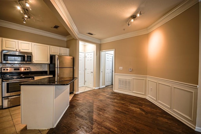 kitchen with stainless steel appliances, white cabinets, visible vents, and decorative backsplash