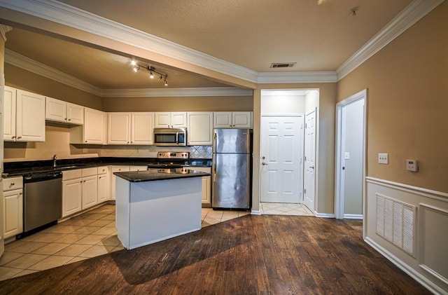 kitchen with crown molding, visible vents, appliances with stainless steel finishes, white cabinetry, and a sink