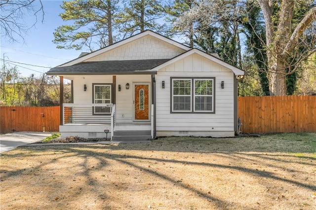 bungalow-style house featuring fence, roof with shingles, covered porch, a front yard, and crawl space