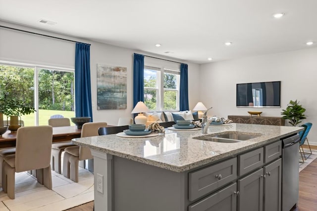 kitchen with gray cabinetry, a kitchen island with sink, sink, light hardwood / wood-style flooring, and dishwasher