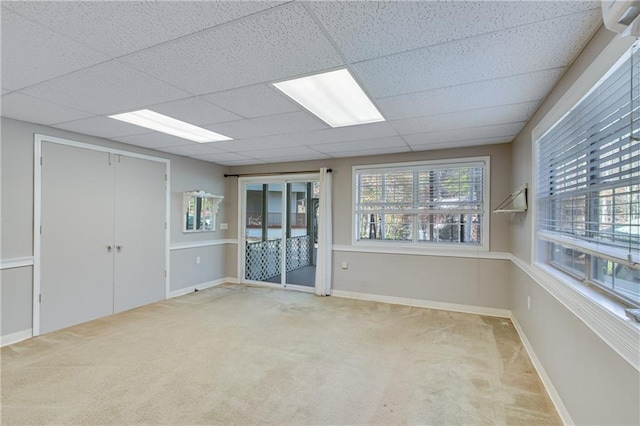 carpeted empty room featuring a drop ceiling