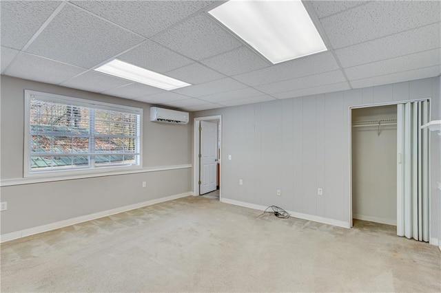 unfurnished bedroom featuring a paneled ceiling, an AC wall unit, light carpet, and a closet