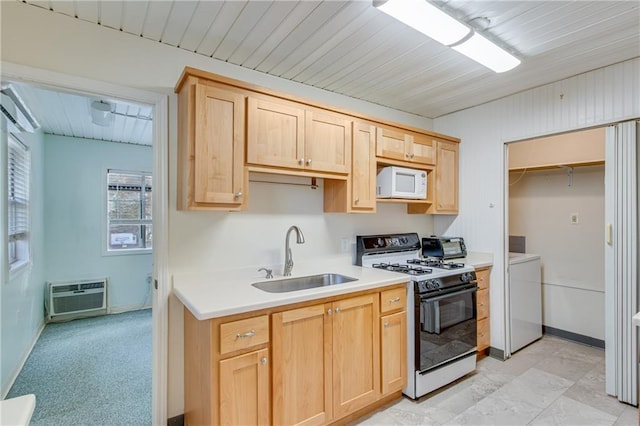 kitchen featuring white appliances, sink, light brown cabinetry, a wall mounted AC, and washer / dryer