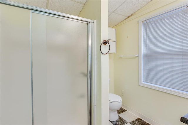 bathroom with tile patterned flooring, a drop ceiling, toilet, and walk in shower