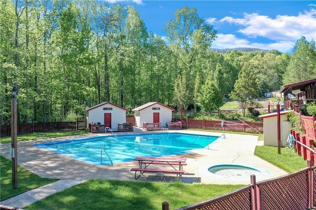 view of pool featuring a lawn, an in ground hot tub, a patio, and a storage shed