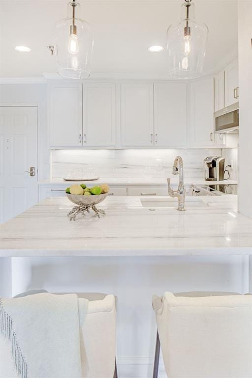300 Johnson Ferry Rd NE Unit A706, Atlanta, GA 30328 - kitchen featuring white cabinets, a kitchen bar, and pendant lighting