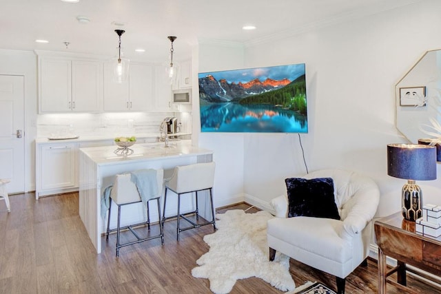 300 Johnson Ferry Rd NE Unit A706, Atlanta, GA 30328 - kitchen with stainless steel microwave, a breakfast bar area, white cabinetry, light countertops, and ornamental molding
