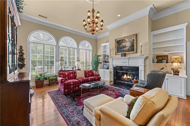 2117 Stephens Walk, Dunwoody, GA 30338 - living area with ornamental molding, built in shelves, a premium fireplace, a chandelier, and light wood-style flooring