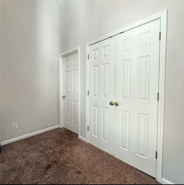 unfurnished bedroom featuring carpet floors, baseboards, and a closet