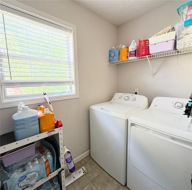 clothes washing area featuring baseboards, light tile patterned flooring, laundry area, and washer and clothes dryer