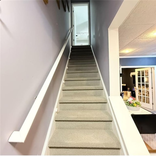 stairway featuring a drop ceiling