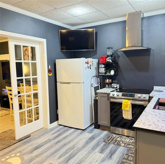 kitchen with wall chimney range hood, stainless steel range with electric stovetop, gray cabinets, light wood-style flooring, and freestanding refrigerator