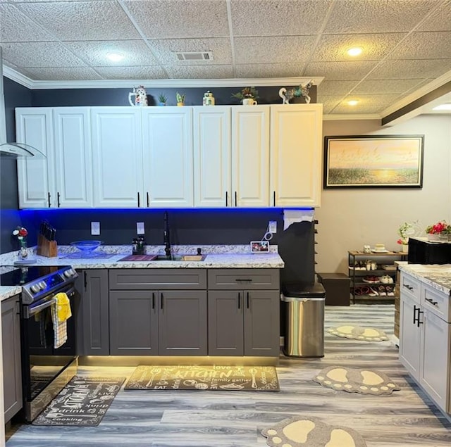 kitchen featuring visible vents, a sink, stainless steel electric range, and ornamental molding