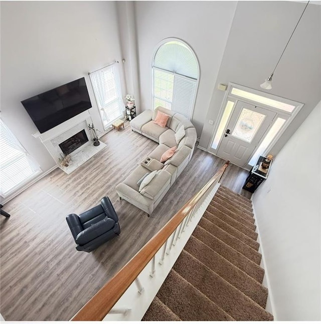 living area featuring a high ceiling, wood finished floors, stairway, and a fireplace