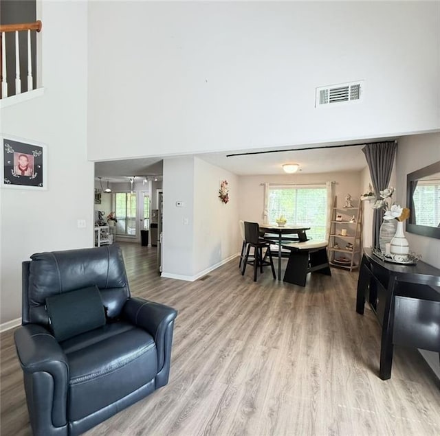living area with a towering ceiling, baseboards, wood finished floors, and visible vents