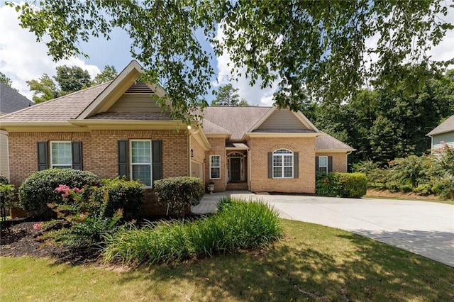 view of front of property featuring roof with shingles, concrete driveway, and brick siding