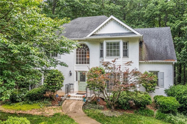 view of front of house featuring brick siding and roof with shingles