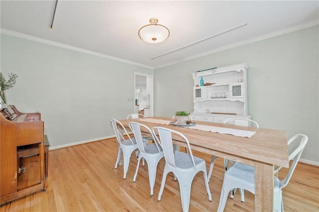 dining area with crown molding, light wood-type flooring, and baseboards