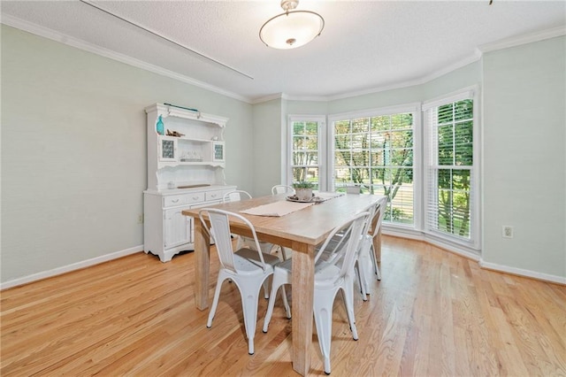 dining space featuring light wood-style flooring, baseboards, ornamental molding, and a textured ceiling