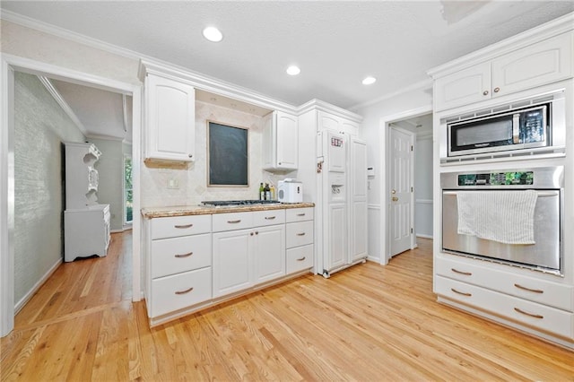 kitchen featuring stainless steel appliances, ornamental molding, white cabinetry, light wood-style floors, and baseboards