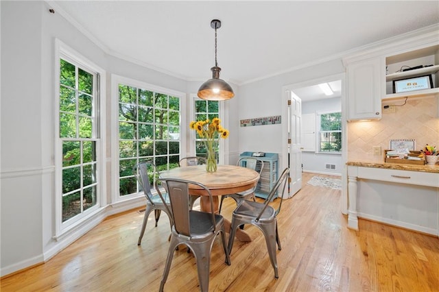 dining space featuring light wood finished floors, baseboards, and ornamental molding