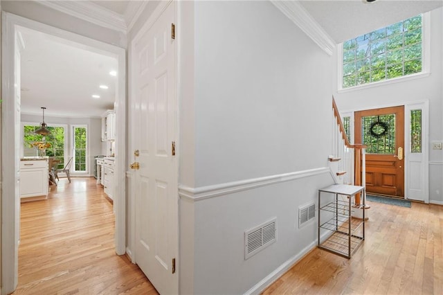 foyer entrance with crown molding, light wood-style floors, stairway, and recessed lighting