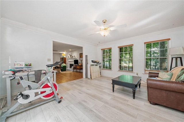 living area with crown molding, plenty of natural light, wood finished floors, and a ceiling fan