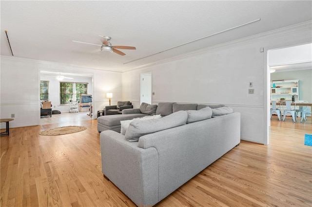 living area with ceiling fan, light wood-style flooring, and ornamental molding